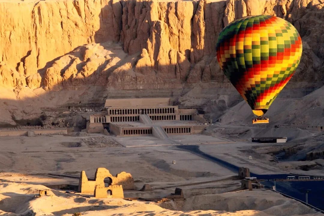 Hot air balloon drifting above Hatshepsut temple and the cliffs of Deir el-Bahari