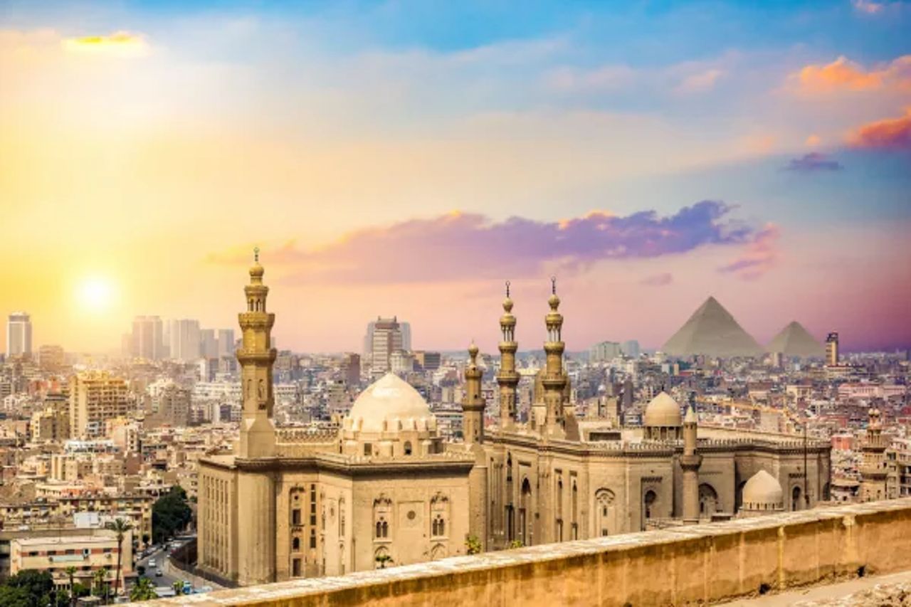 Cairo mosques and skyline at sunset with the pyramids faint on the horizon