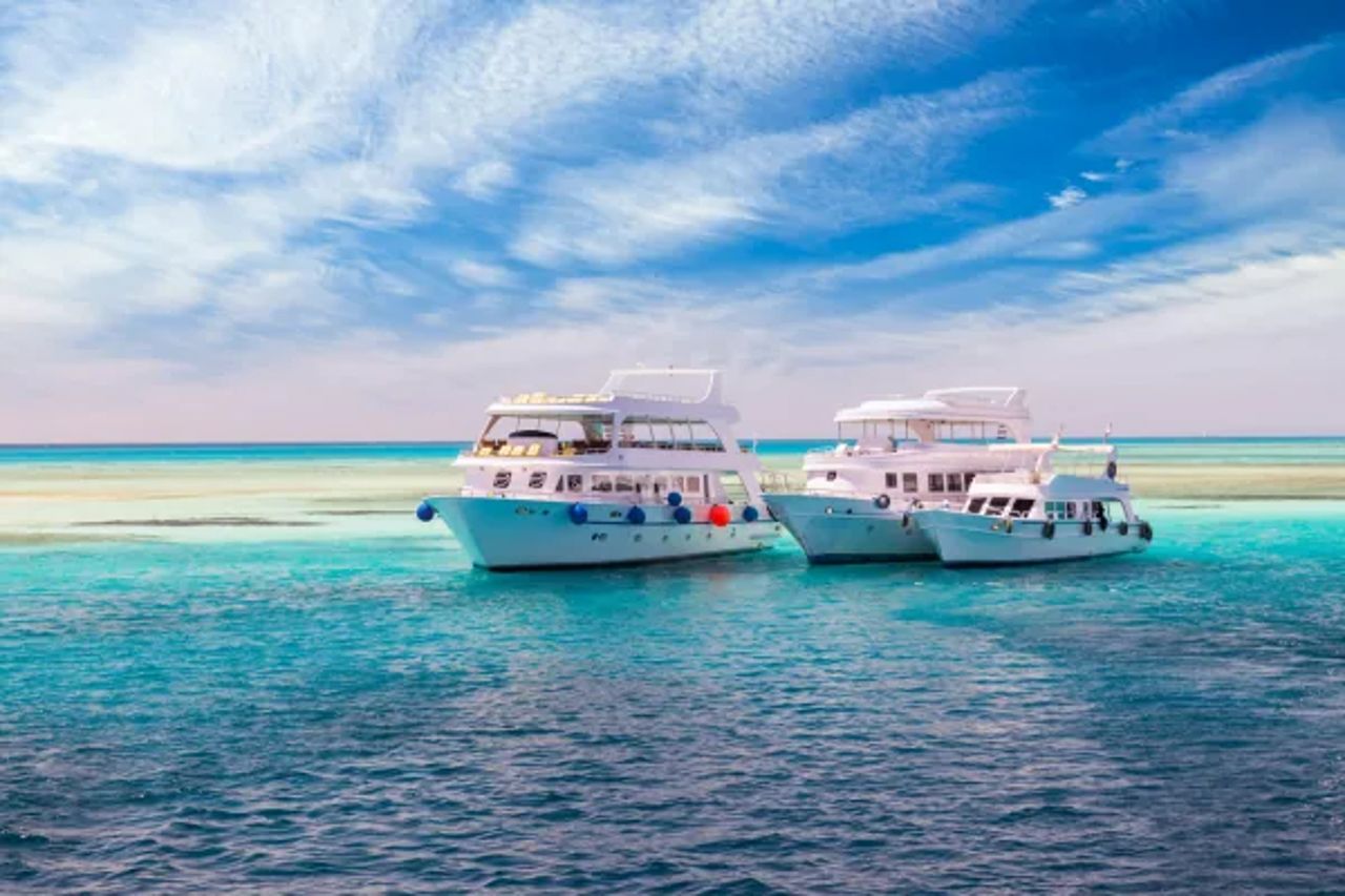 Three white day boats moored on shallow turquoise water