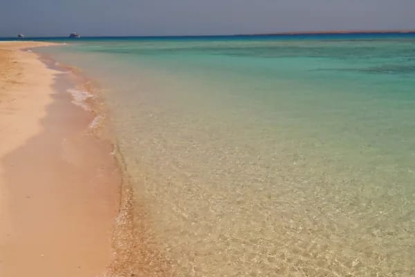 Pale sand and shallow clear water on a Giftun island beach