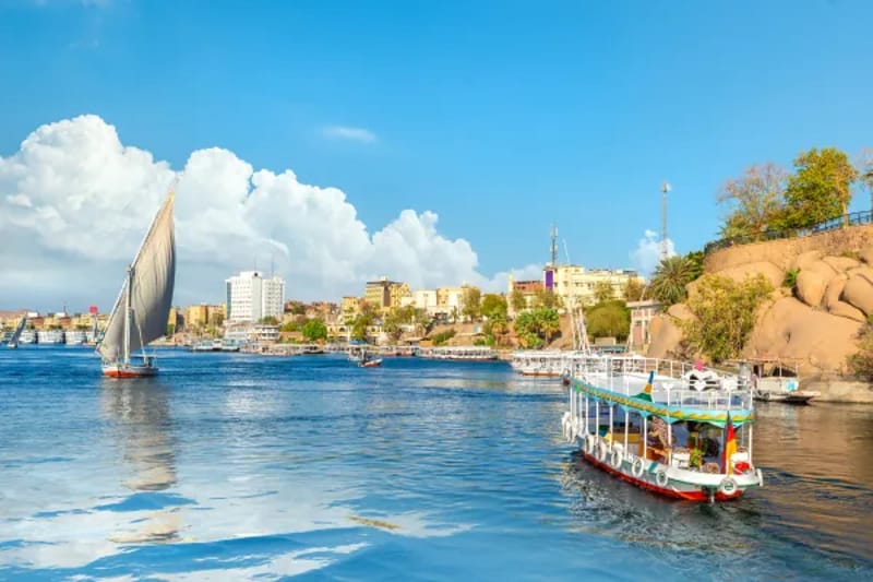 Aswan riverfront with a felucca and a tourist boat on the Nile