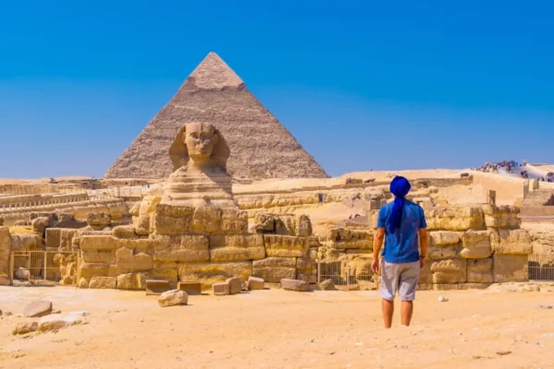 Man standing in front of the Sphinx and a pyramid at Giza
