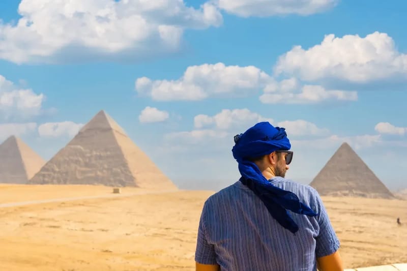 Traveller in a blue headscarf looking toward the pyramids of Giza
