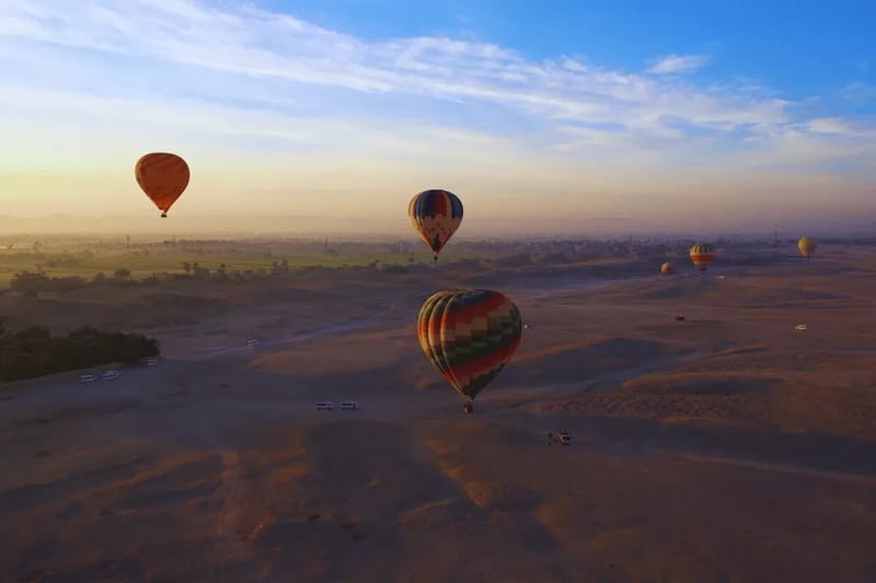 Hot air balloons rising over the Luxor west bank at dawn